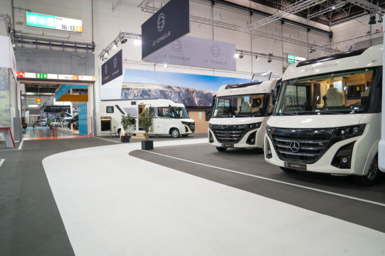 Messestand von Le Voyageur mit zwei weißen Integrierten auf Mercedes-Basis