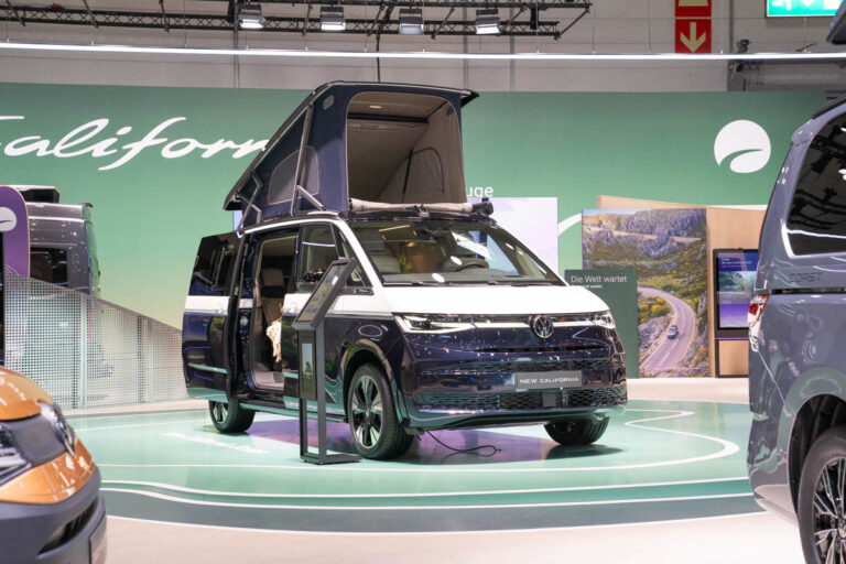 Dunkelblauer VW California mit aufgestelltem Dach auf dem Messestand von Volkswagen