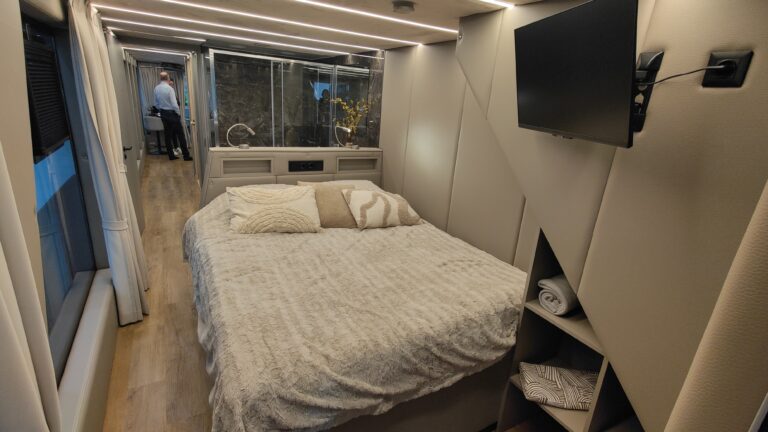 Schlafzimmer eines Hausbootes mit Doppelbett, Wandfernseher und indirekter Beleuchtung
