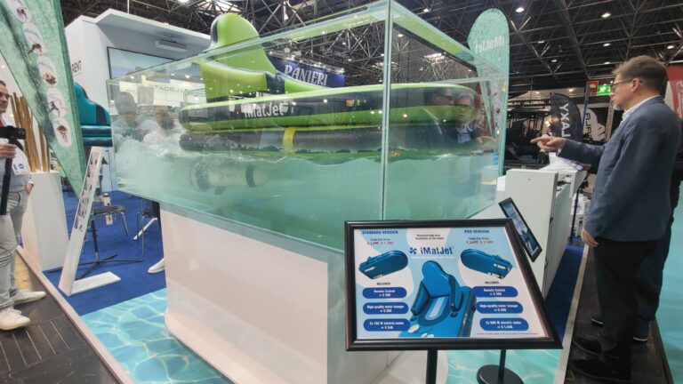 Grünes Motor-Schwimmbrett iMatJet in einem gläsernen Wasserbecken auf dem Messestand