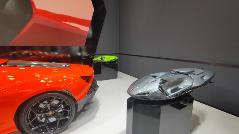 Roter Lamborghini-Sportwagen neben einem grauen Wassermotorrad-Konzept auf einem Podest