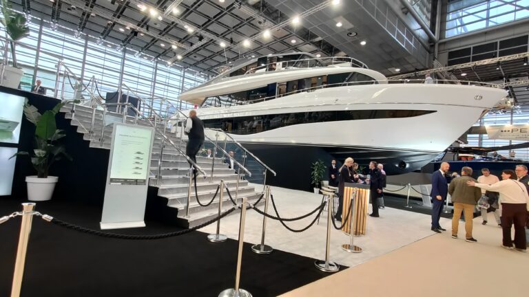 Große weiße Motoryacht mit Besuchertreppe zum Betreten auf dem Messestand